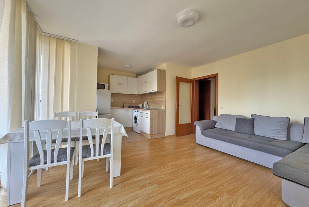 Светлая квартира с открытой планировкой, кухней, обеденным столом и диваном, полы из дерева.