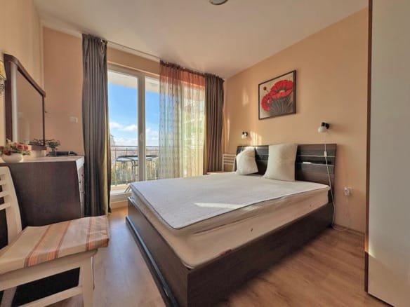 Светлая спальня с двуспальной кроватью, окнами на балкон с видом, современная мебель, идеально подходит для апартаментов у моря в Болгарии.