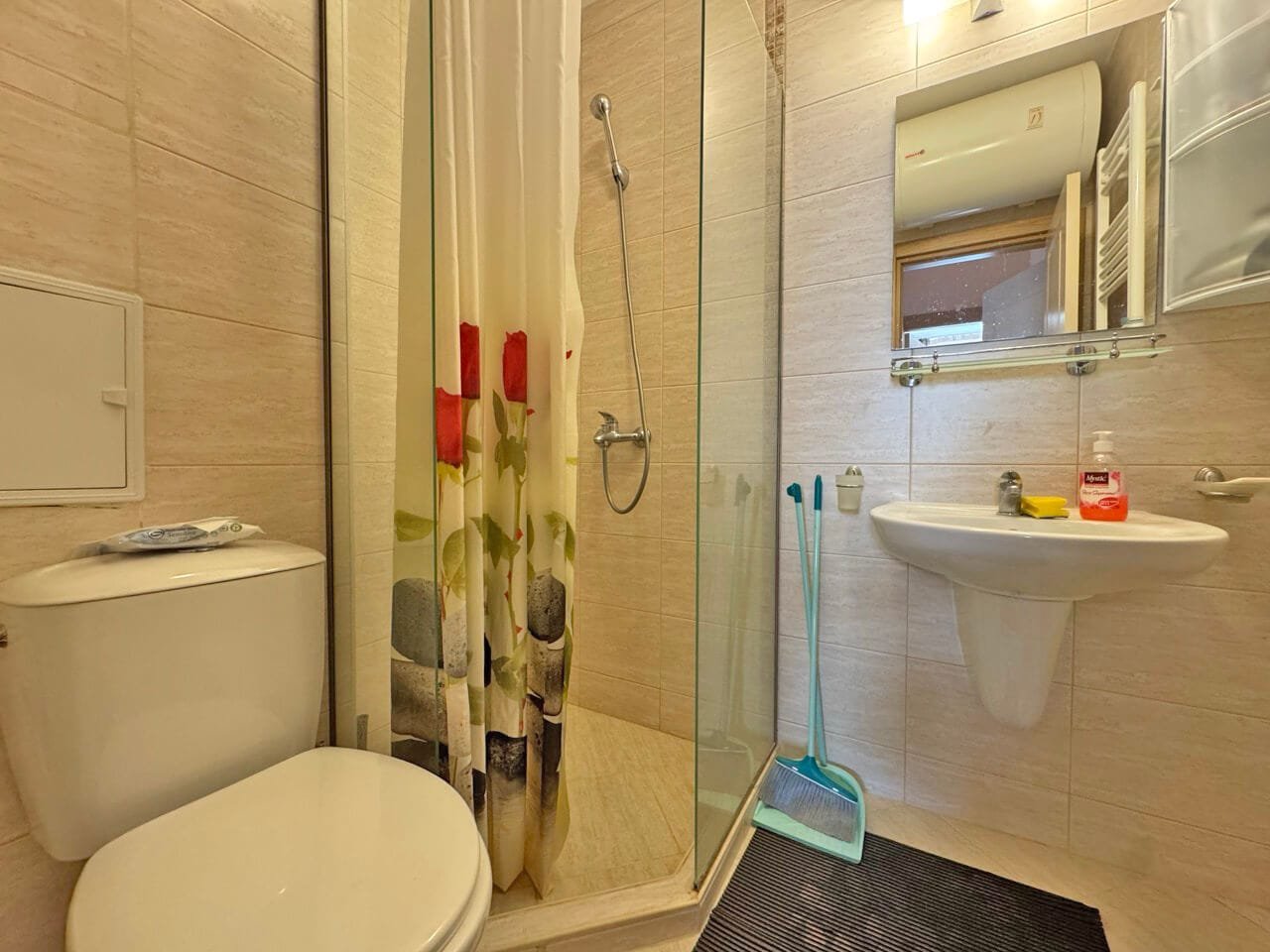 Современная ванная комната с душевой кабиной, унитазом и раковиной, оформленная в светлых тонах, идеальна для апартаментов в Болгарии.