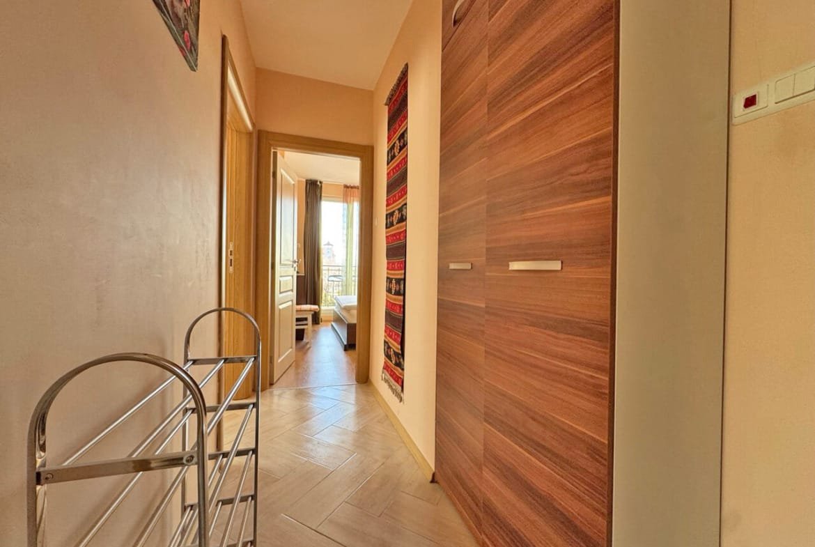 Современный коридор с деревянными шкафами, светлыми стенами и декоративными элементами, создающий уют в квартире у моря.