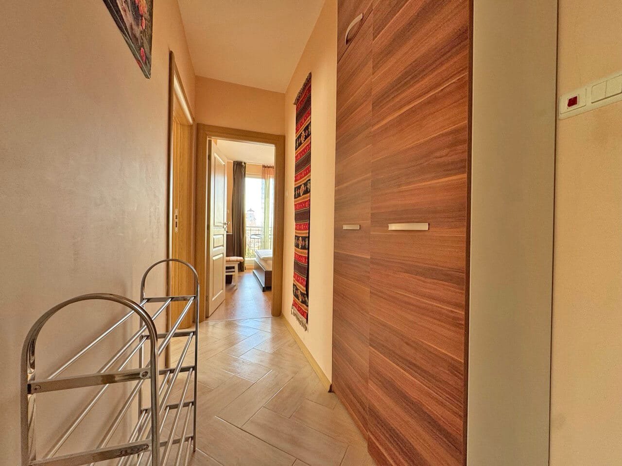 Современный коридор с деревянными шкафами, светлыми стенами и декоративными элементами, создающий уют в квартире у моря.