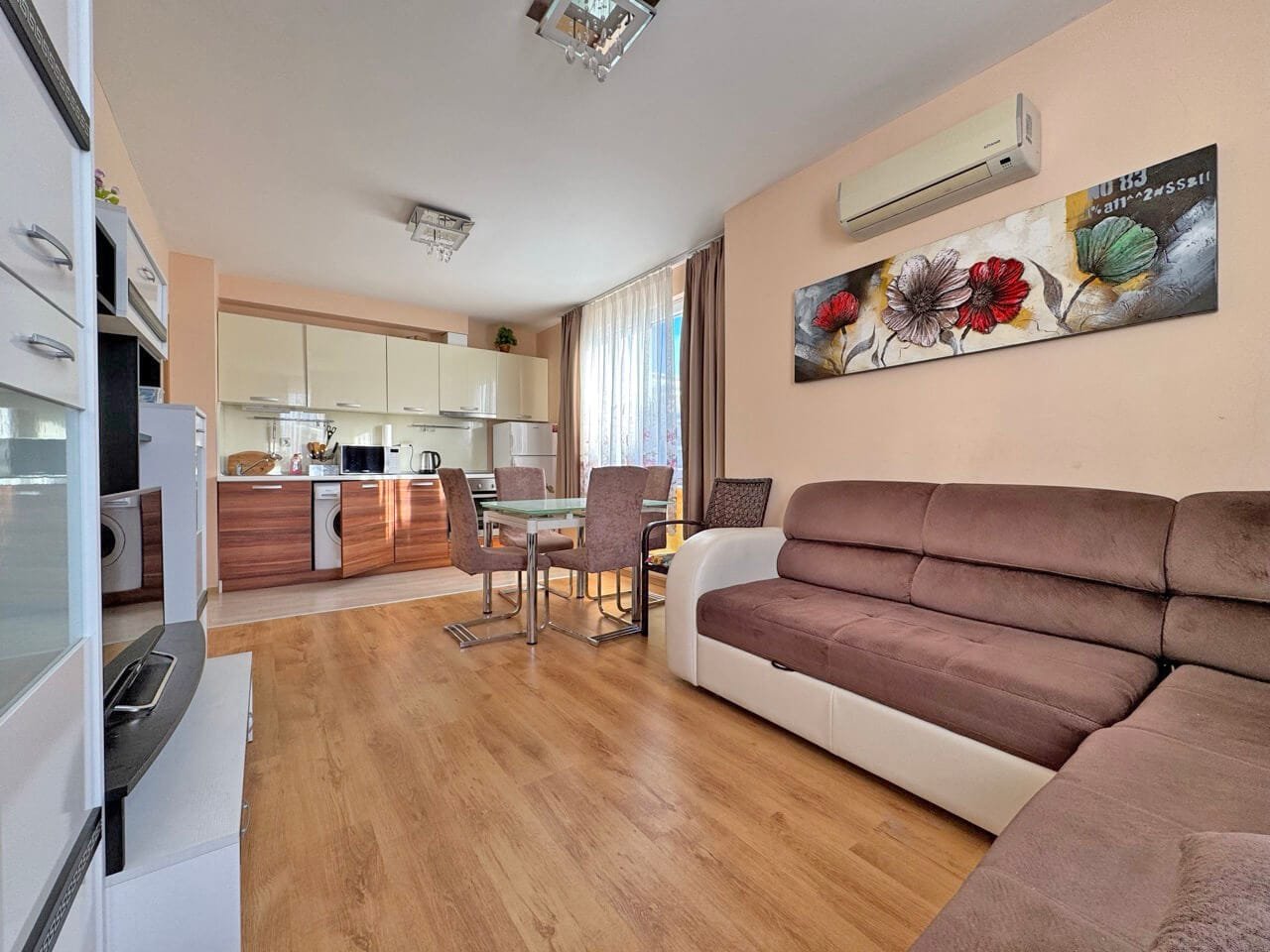 Современная квартира с открытой планировкой, гостиная с диваном и обеденной зоной, интерьер в светлых тонах, недалеко от моря.