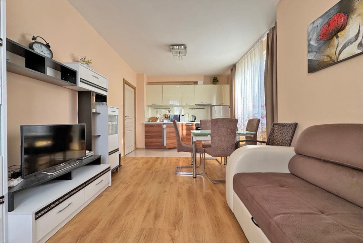 Современная гостиная с уютным диваном, обеденным столом и кухонной зоной, расположенная в квартире.