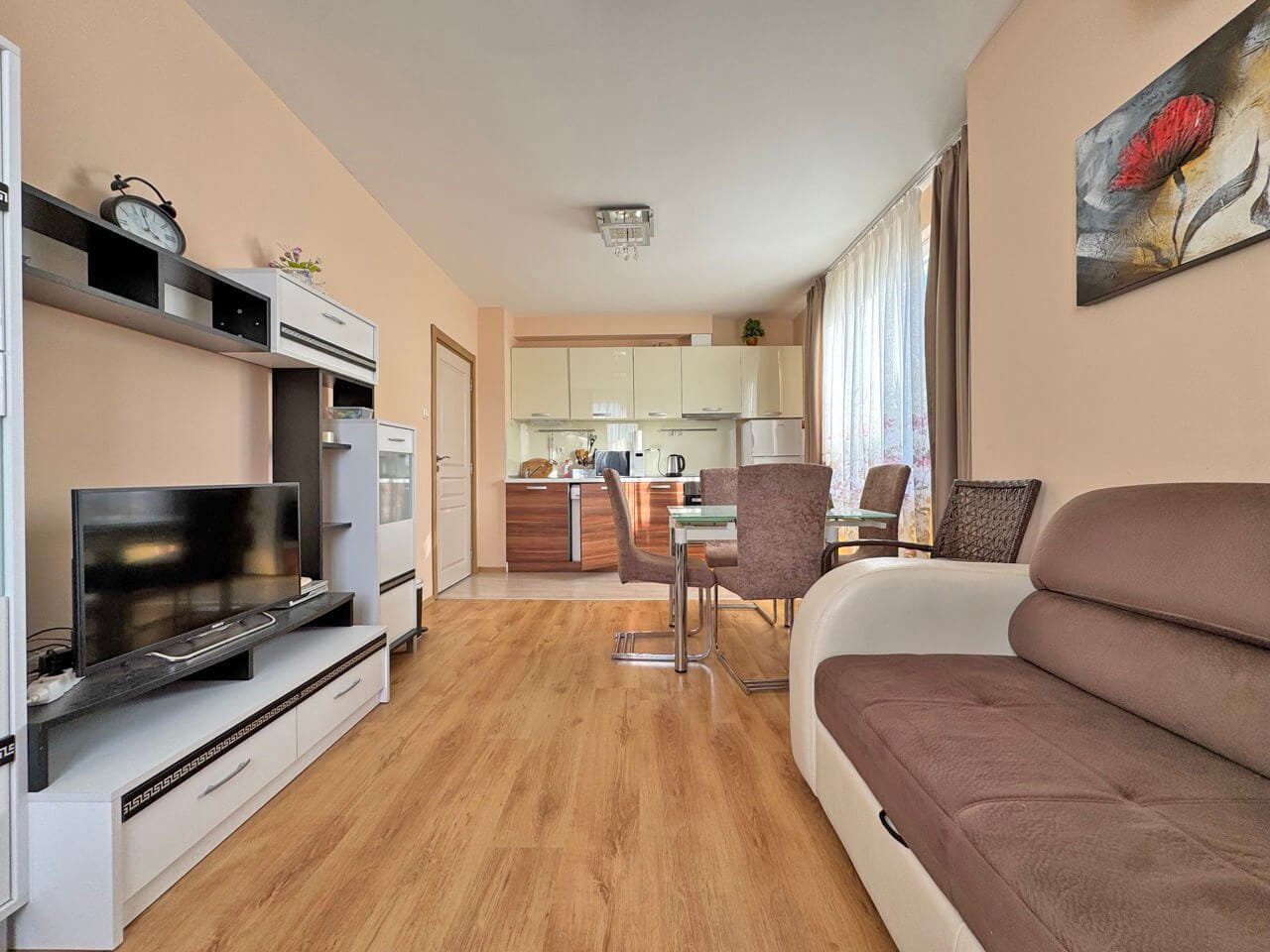 Современная гостиная с уютным диваном, обеденным столом и кухонной зоной, расположенная в квартире.