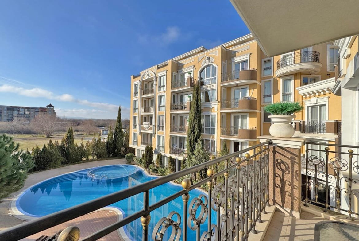 Балкон с видом на бассейн и зелёные насаждения в комплексе апартаментов в Болгарии, близко к морю.