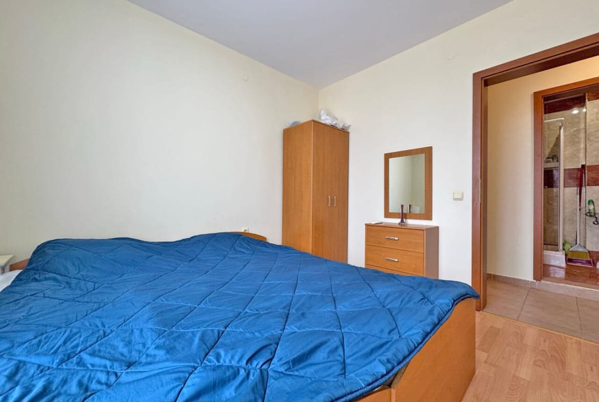 Спальня с двуспальной кроватью, шкафом, комодом и ванной в углу. Преобладают светлые оттенки синих и коричневых цветов.