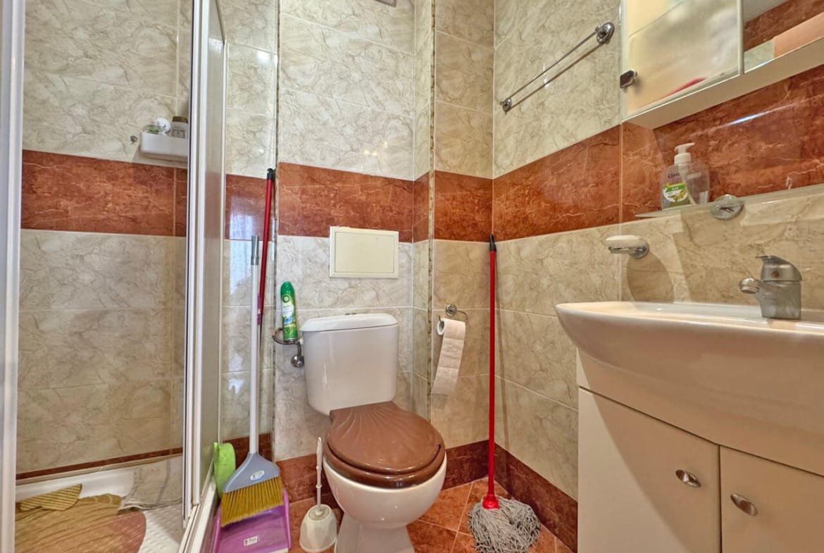 Современная ванная комната с душевой кабиной, унитазом и раковиной, стены отделаны плиткой в светлых и коричневых оттенках.