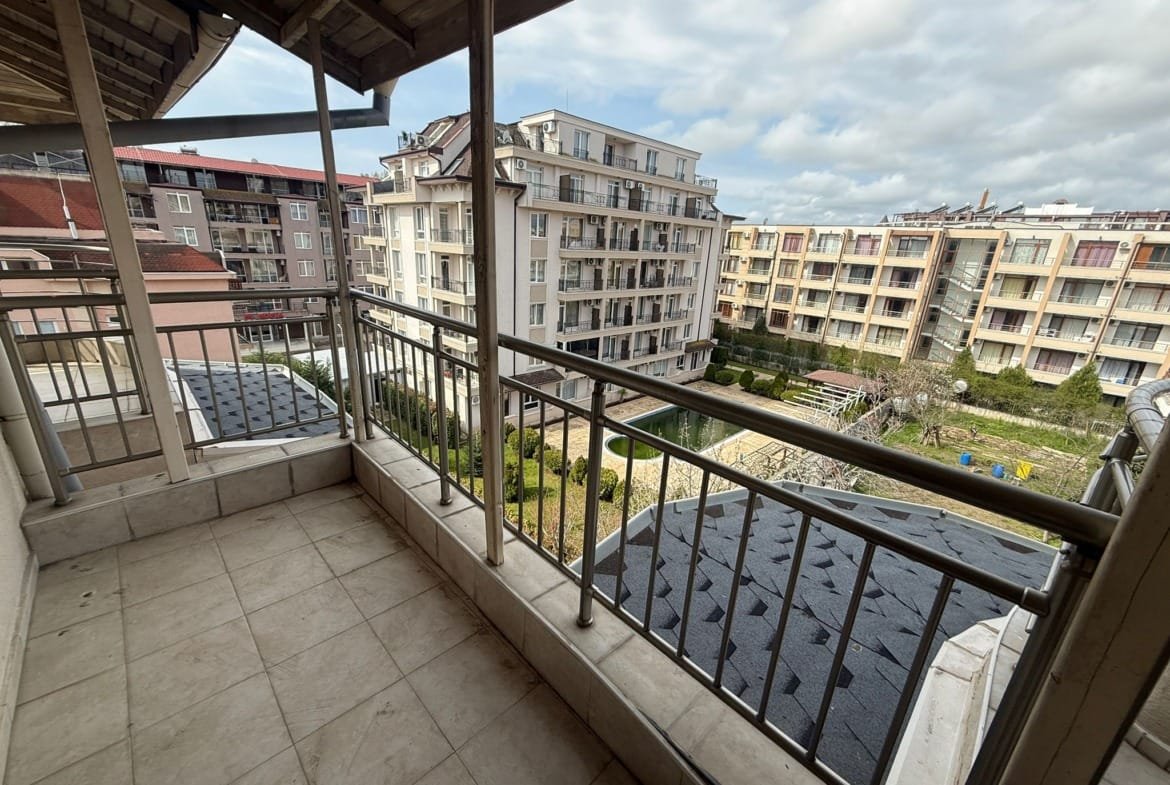 Балкон с металлическим перилами, вид на современный жилой комплекс и ухоженный двор в Болгарии. Отличное предложение для покупки недвижимости.
