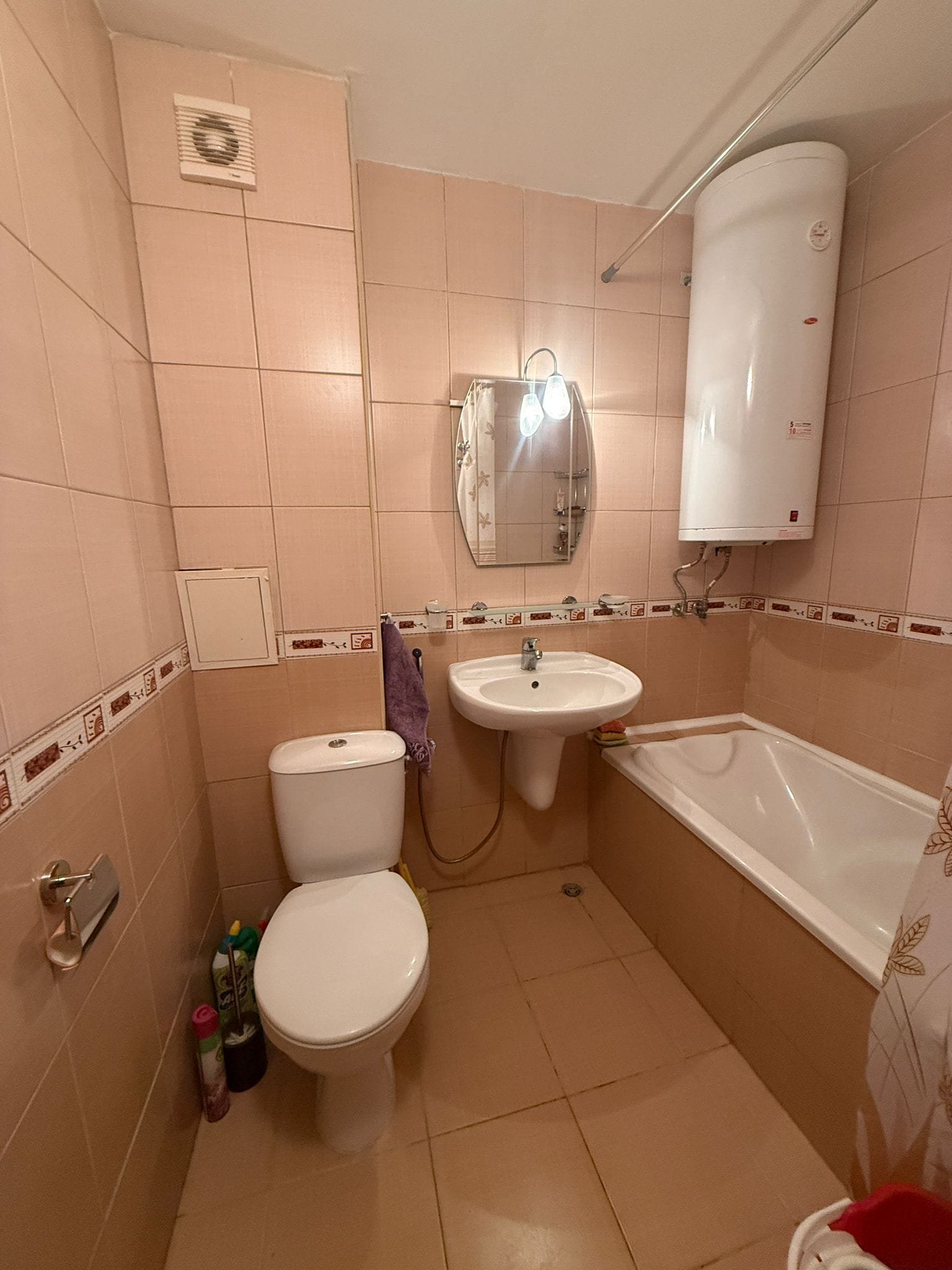 Современная ванная комната с ванной, раковиной и унитазом, оформленная в светлых тонах, подходящая для покупки жилья в Болгарии.