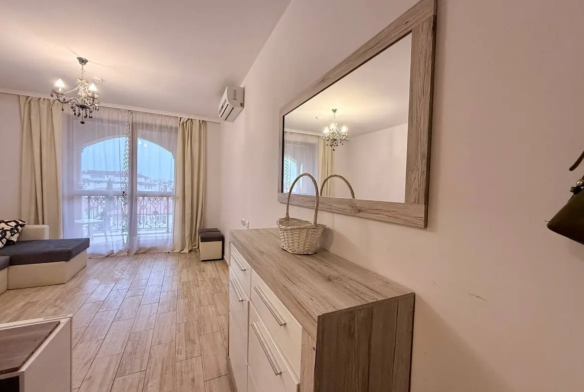 Современный интерьер квартиры в Болгарии с белыми стенами, деревянной мебелью и ярким освещением, идеально подходит для жизни или аренды.