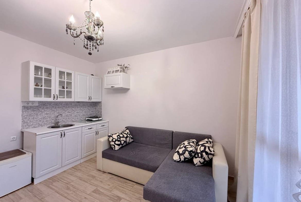 Современная квартира со светлым интерьером, уютным диваном и кухонным гарнитуром, идеально подходящая для продажи в Болгарии.