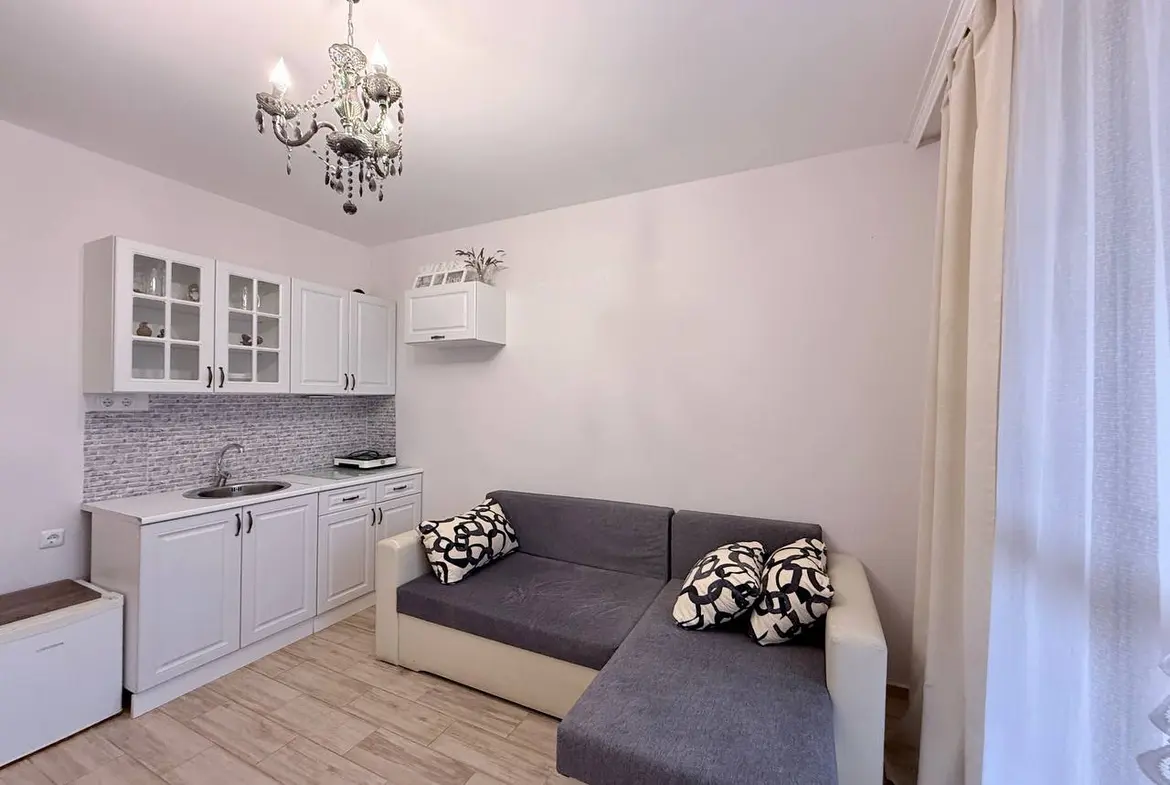 Современная квартира со светлым интерьером, уютным диваном и кухонным гарнитуром, идеально подходящая для продажи в Болгарии.