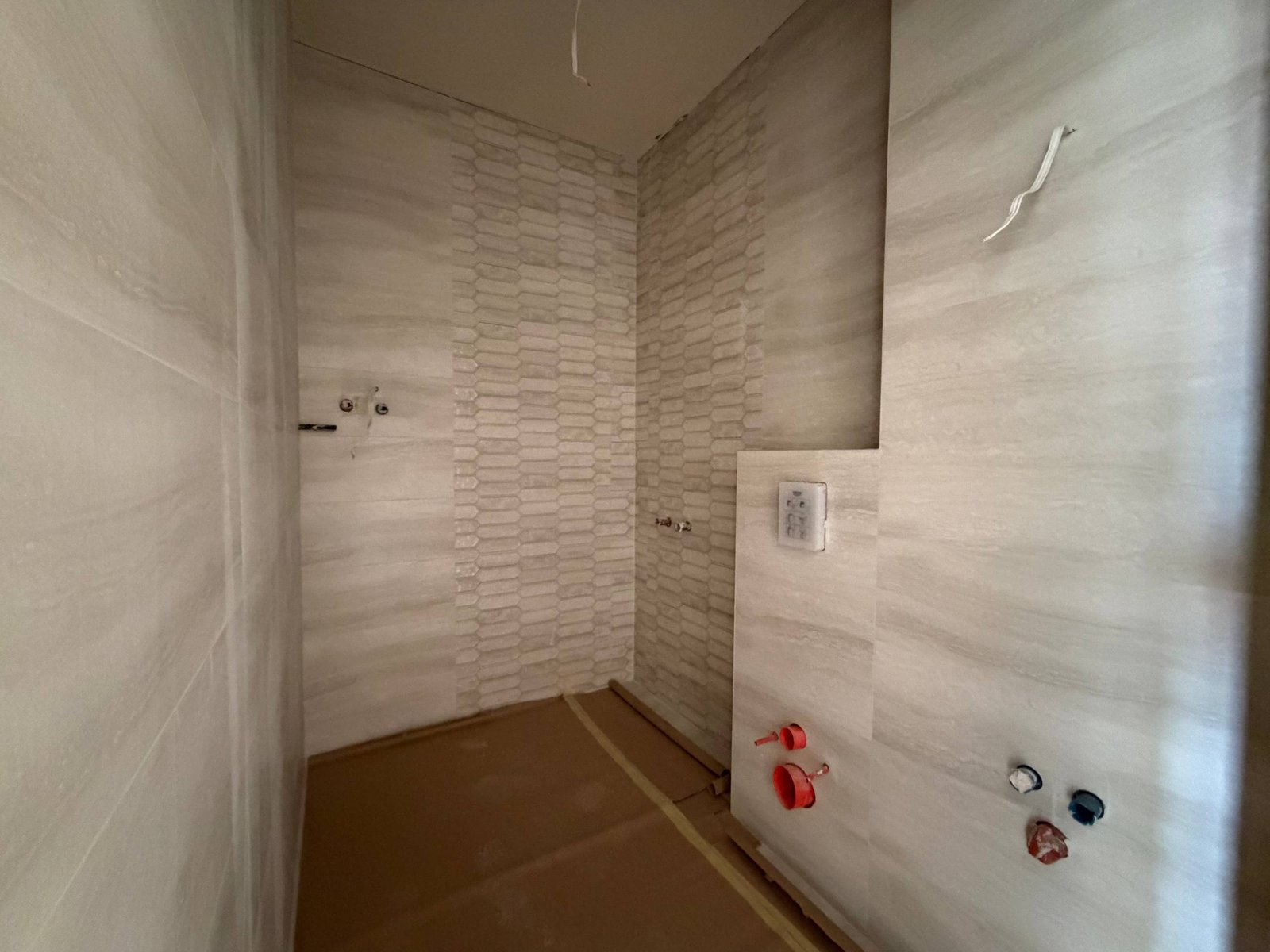 Современный интерьер ванной комнаты в студии, отделка светлыми плитками и установленная сантехника.