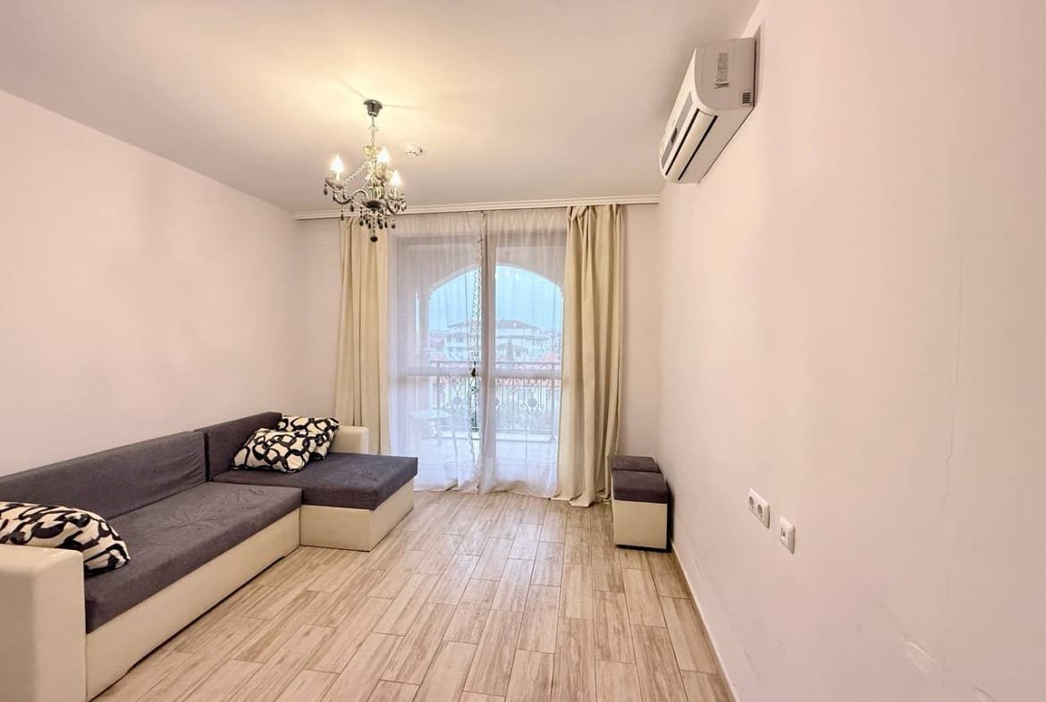 Светлое помещение с диваном, с балконной дверью и современным дизайном, идеально для покупки недвижимости в Болгарии.