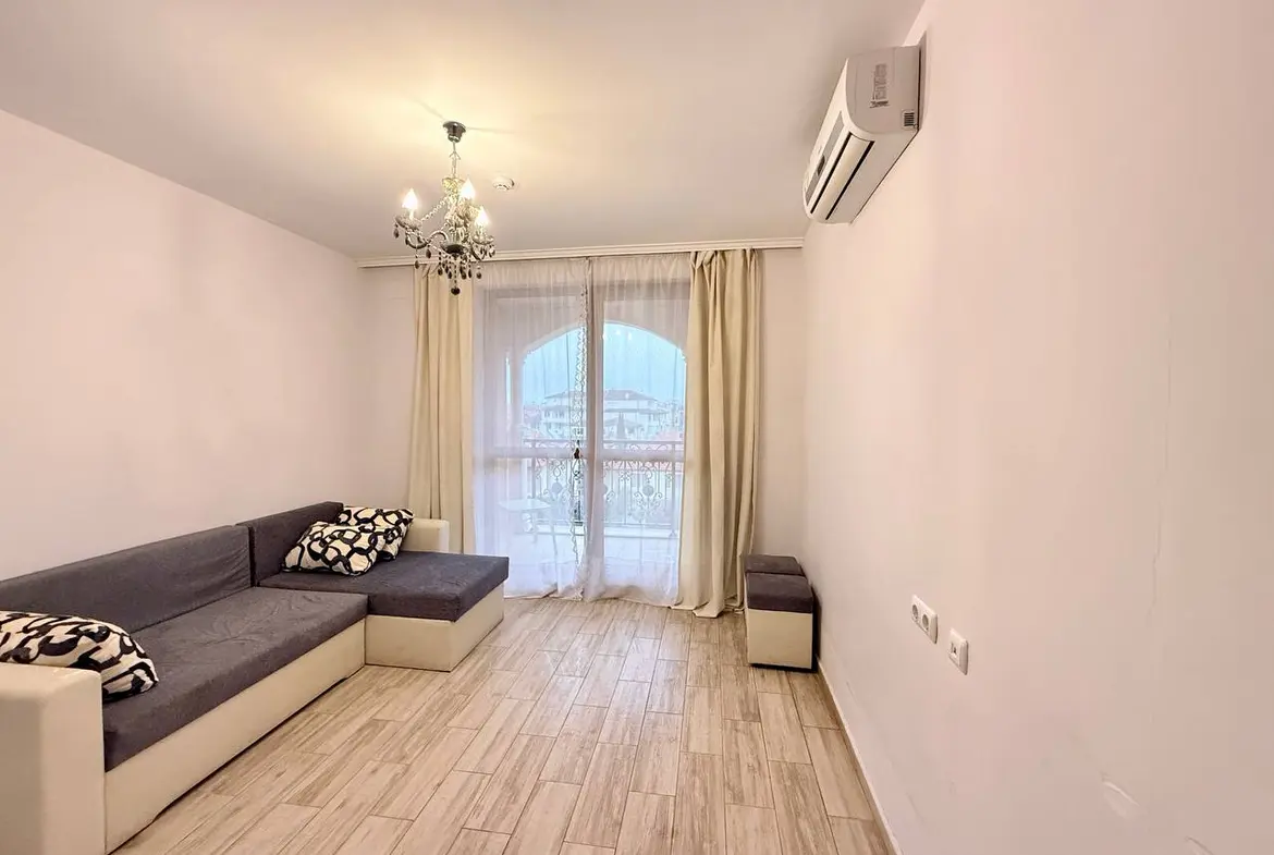 Светлое помещение с диваном, с балконной дверью и современным дизайном, идеально для покупки недвижимости в Болгарии.