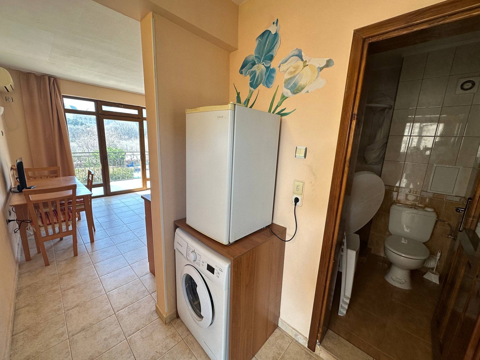 Двухкомнатный апартамент с белым холодильником, стиральной машиной и ванной, которые создают комфортную атмосферу.