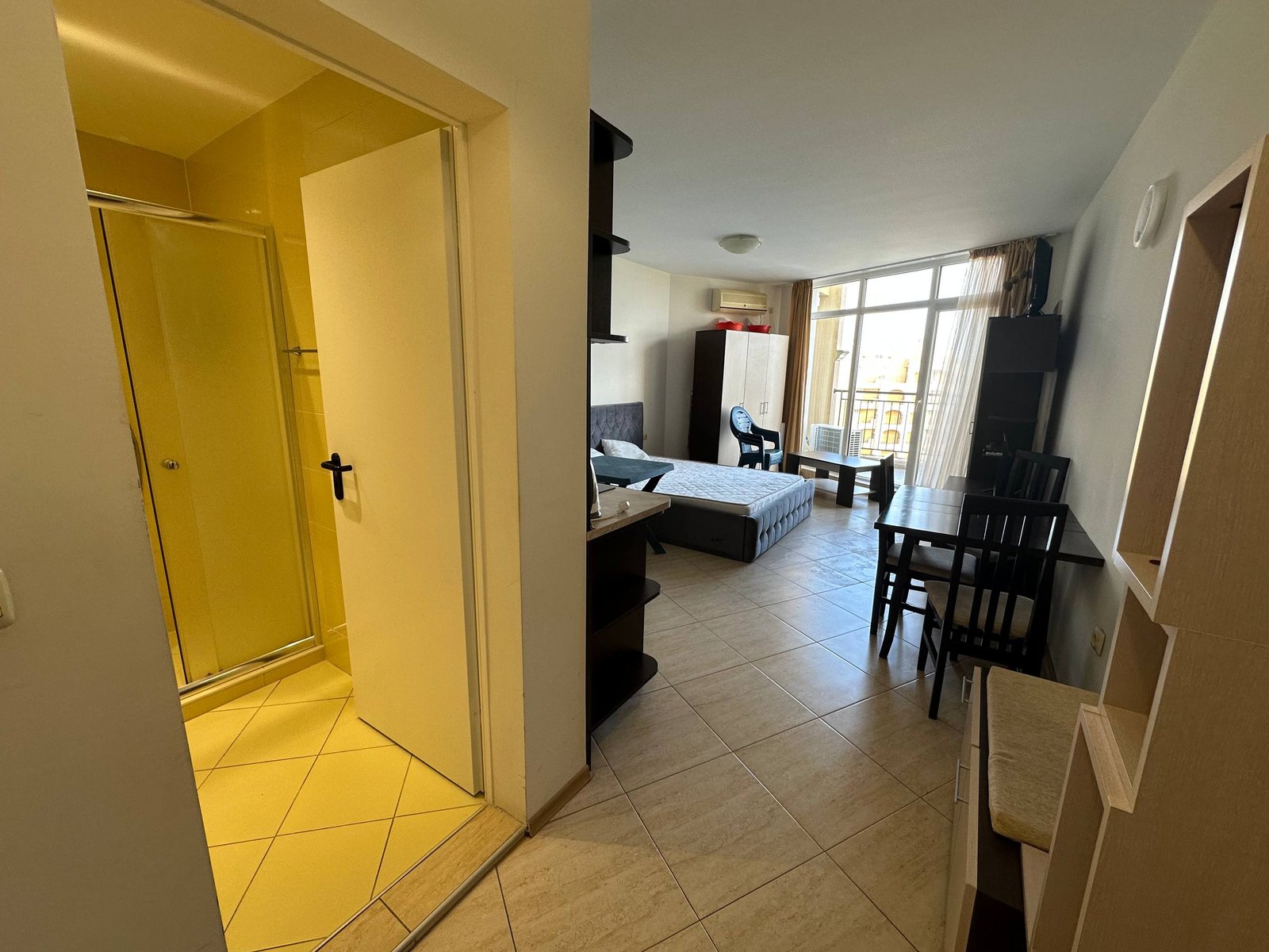 Современная студия с открытой планировкой, кухонным уголком, обеденной зоной и ванной, много света и простор.