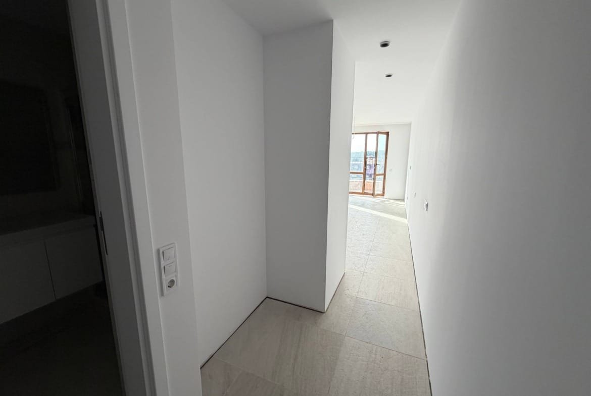 Современный коридор студии с белыми стенами, светлым полом и окнами, пропускающими естественный свет.