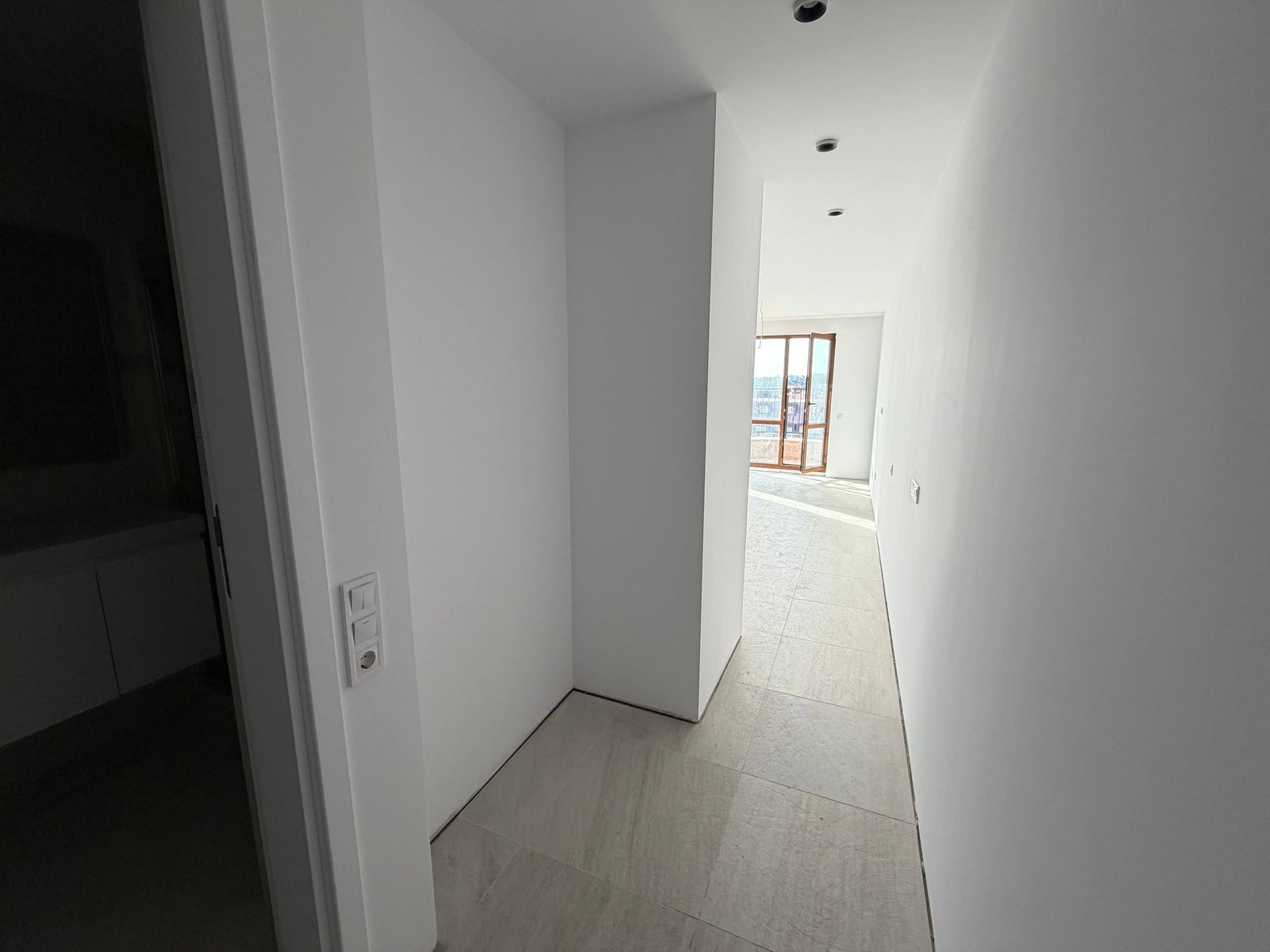 Современный коридор студии с белыми стенами, светлым полом и окнами, пропускающими естественный свет.