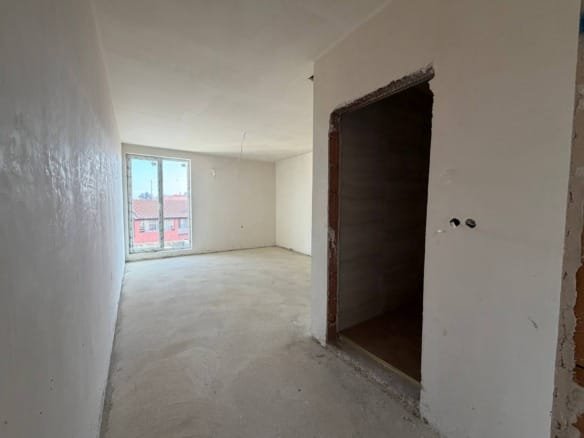 Пустая квартира в комплексе La Mer Gold с белыми стенами, светлым полом и большими окнами, обеспечивающими естественное освещение.