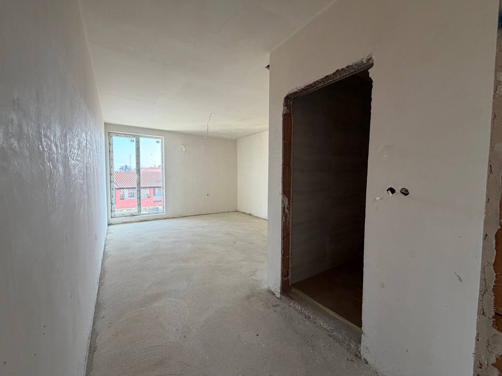 Пустая квартира в комплексе La Mer Gold с белыми стенами, светлым полом и большими окнами, обеспечивающими естественное освещение.