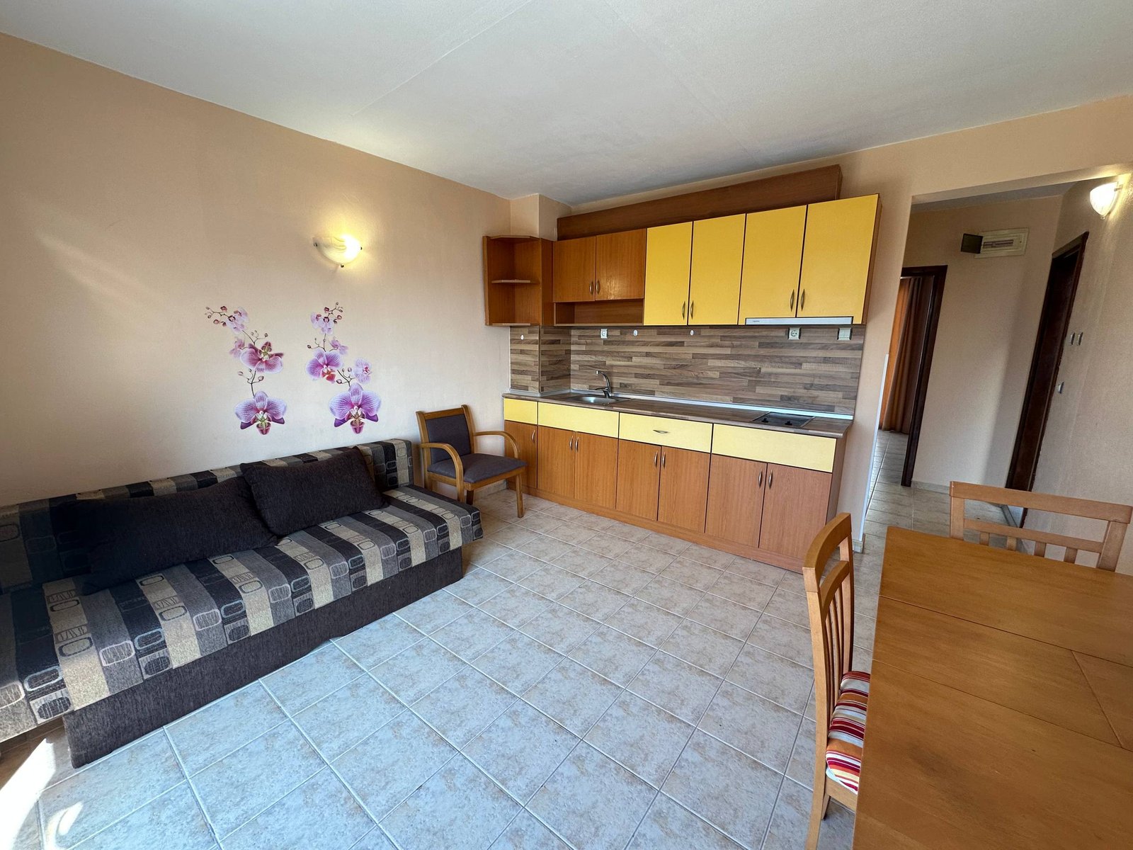 Современный двухкомнатный апартамент в комплексе с кухней, обеденной зоной и уютным диваном, оформленный в светлых тонах.