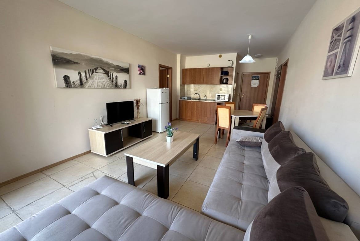 Современный трехкомнатный апартамент с белыми стенами, мягкой мебелью, кухней и телевизором, яркое освещение и уютный интерьер.