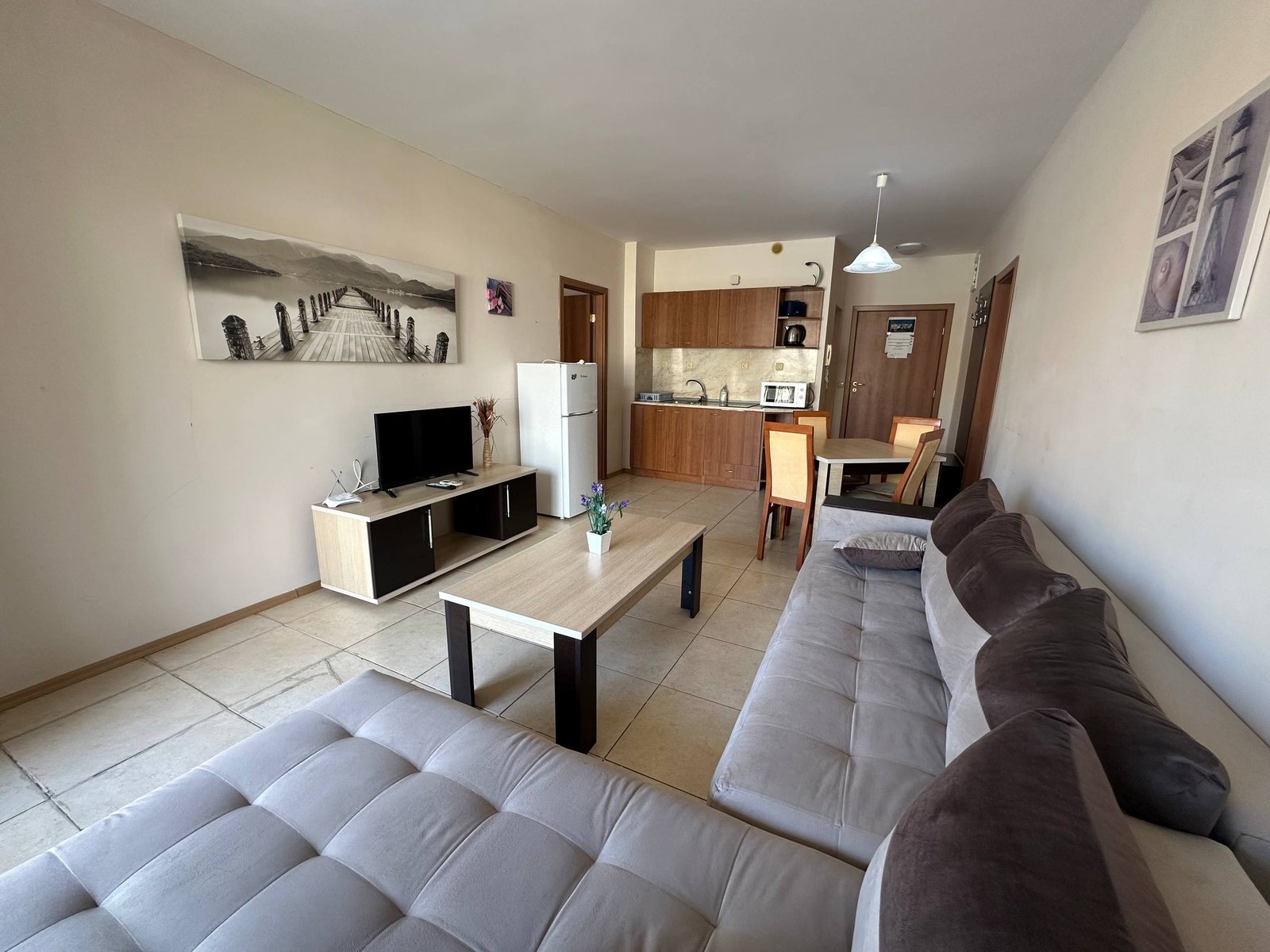 Трехкомнатный апартамент в “Midia Family Resort” с комфортной обстановкой Современный трехкомнатный апартамент с белыми стенами, мягкой мебелью, кухней и телевизором, яркое освещение и уютный интерьер.