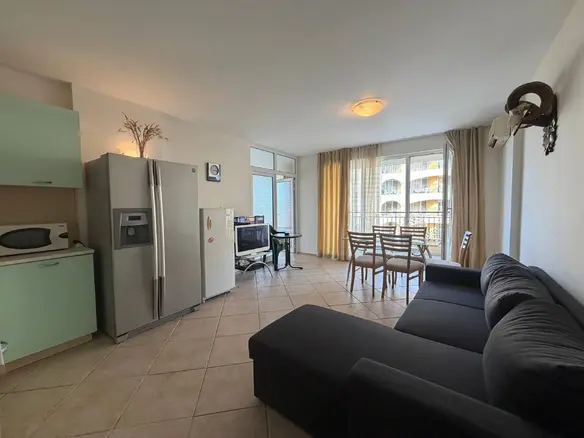 Современный интерьер квартиры с кухней, обеденной зоной и уютной гостиной, светлые тона и большой холодильник.