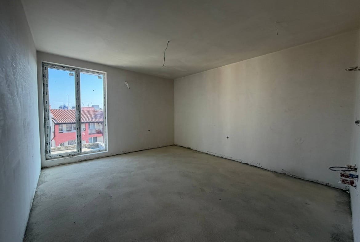 Пустая студия с окнами на улицу, белые стенами и светлым полом, готовая для отделки в комплексе La Mer Gold.