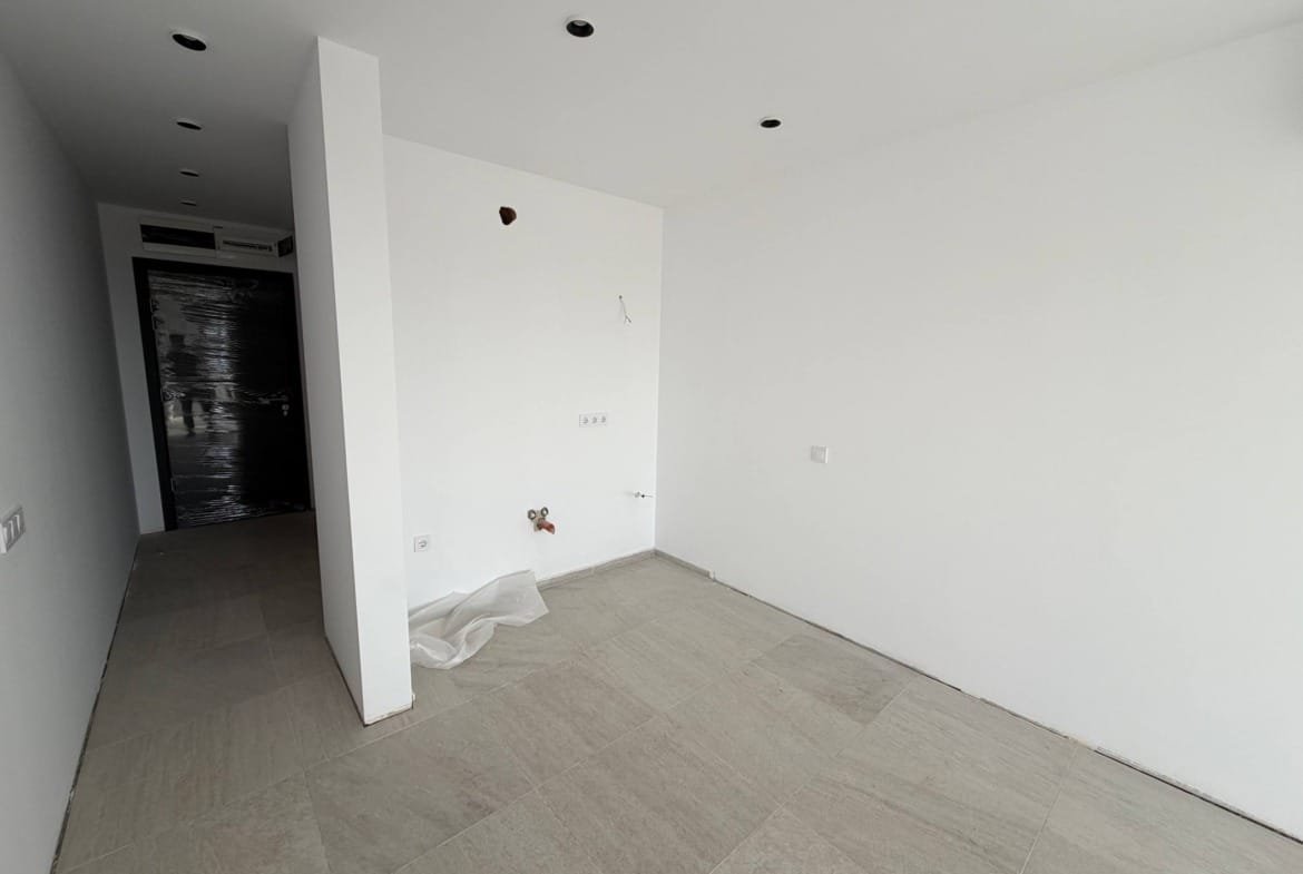 Современно оформленная комната с белыми стенами, плиточным полом, без мебели и декора, готовая для дальнейших работ.