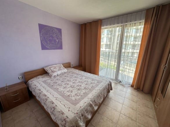 Двухкомнатный апартамент с кроватью, тёплыми тонами и балконом, оформленный современным текстилем и декоративными элементами.