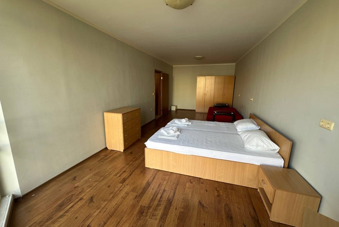 Современная комната с двумя односпальными кроватями, деревянной мебелью и светлыми стенами.