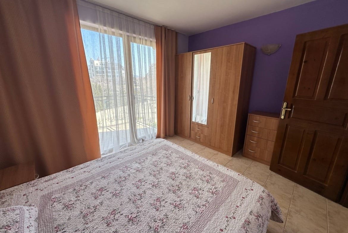 Двухкомнатный апартамент с балконом, светлыми шторами и деревянной мебелью, оформленный в теплых нюансах.