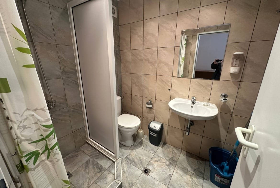 Современная ванная комната с душевой кабиной, унитазом, раковиной и зеркалом на плиточных стенах.