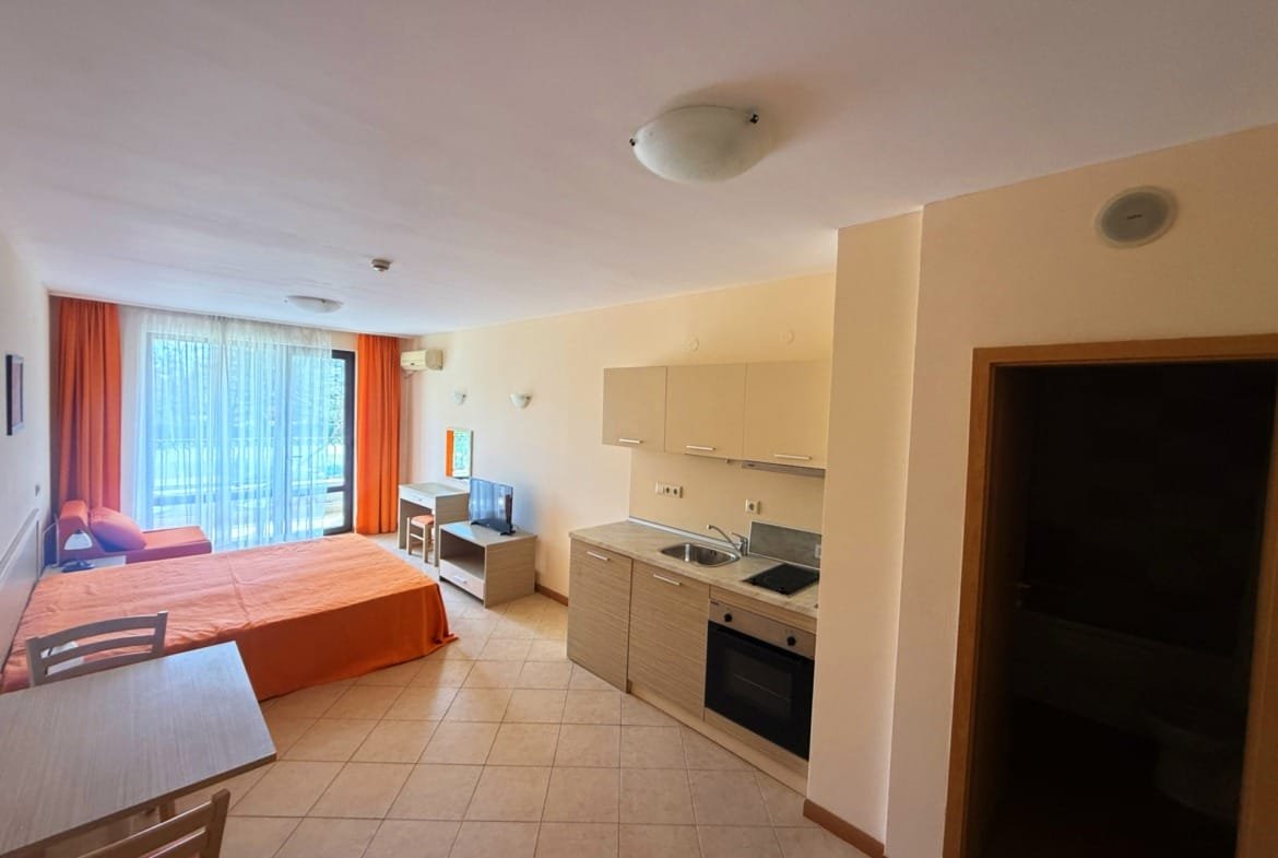 Уютная студия в Болгарии с кухней, столом, диваном и панорамным окном, идеально подходит для продажи или аренды.