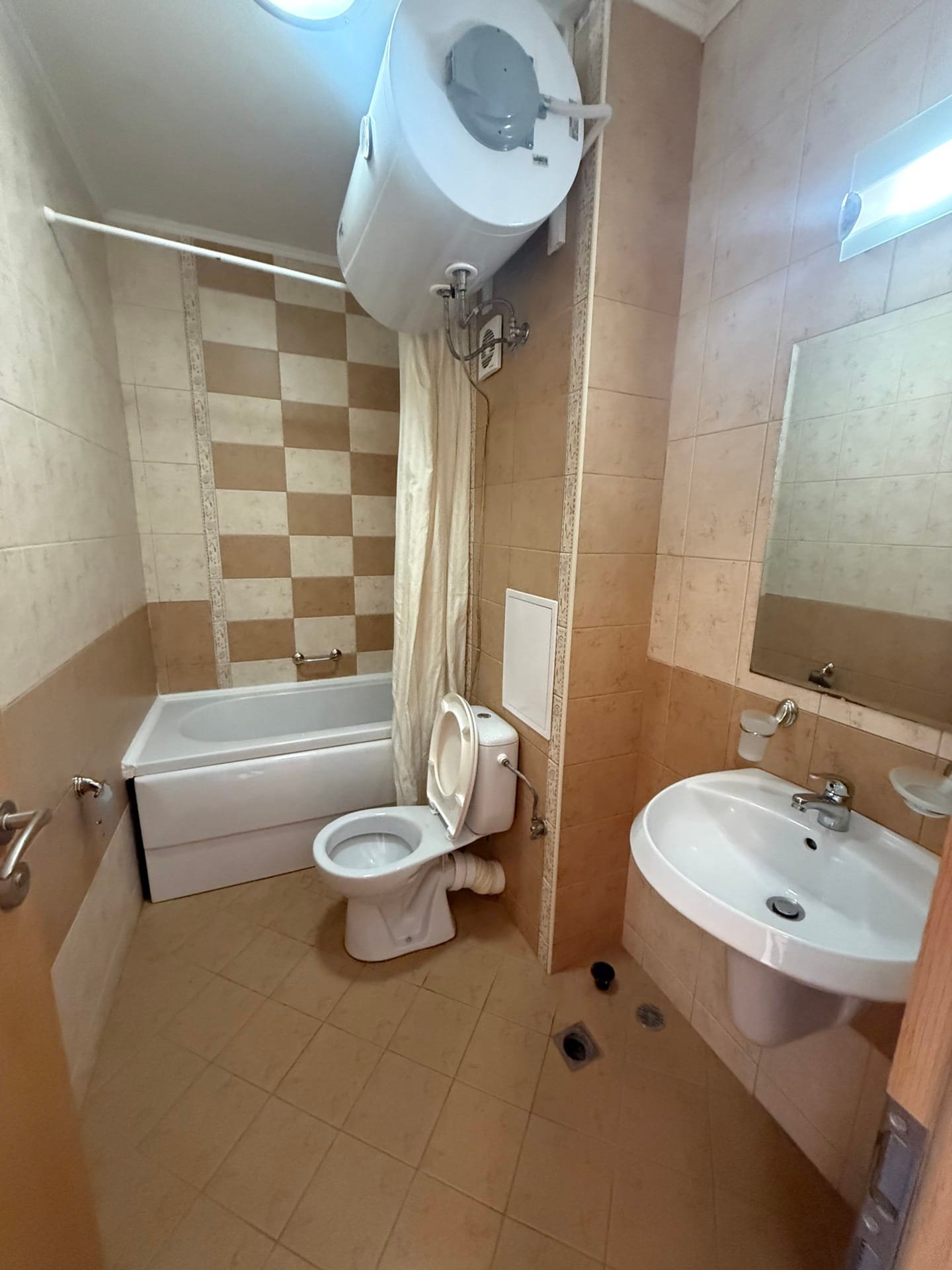 Современная ванная комната с ванной, унитазом и раковиной, оформленная в светлых тонах, идеальна для продажи недвижимости в Болгарии.