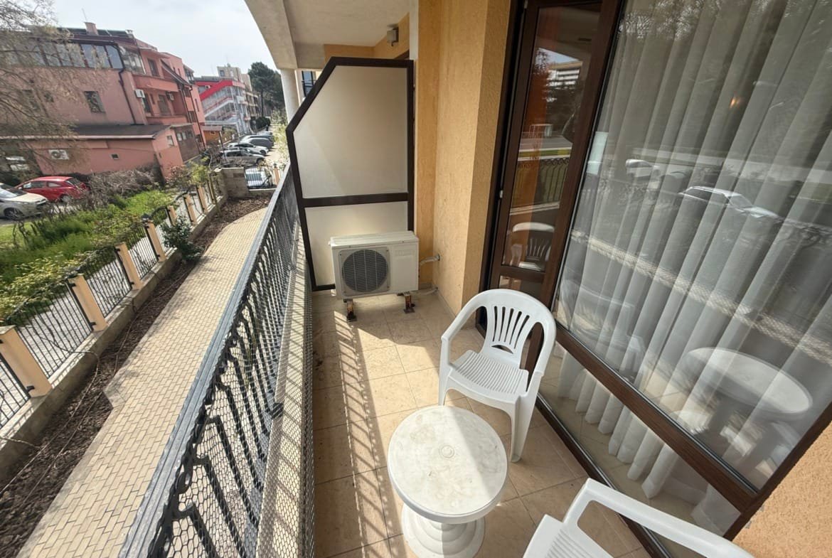 Балкон с белыми пластиковыми стульями и столом, вид на улицу, идеальное место для отдыха в Болгарии.