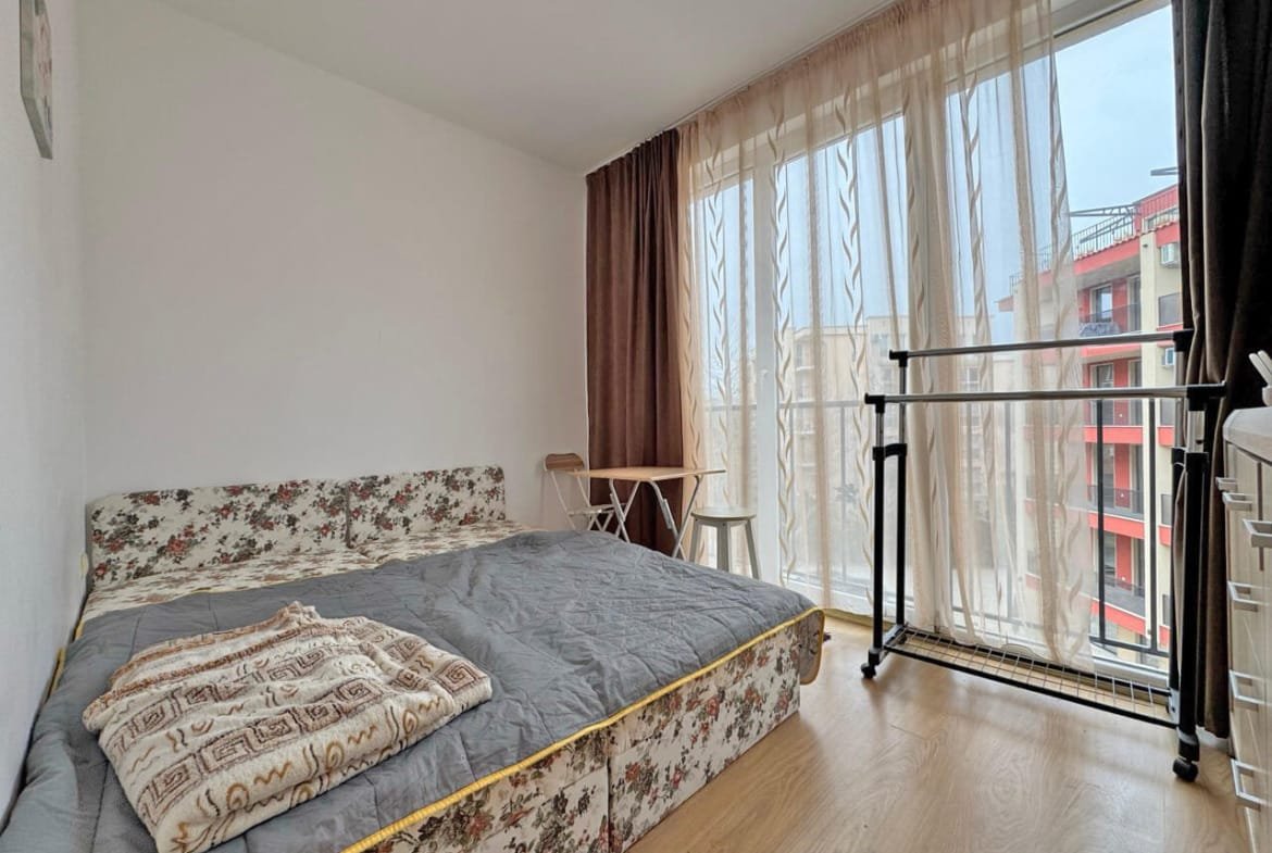 Современная спальня с двуспальной кроватью, большими окнами и светлыми шторами, расположенная в квартире в Святом Власе.