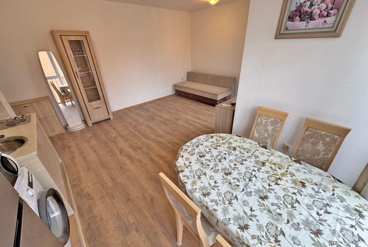 Гостиная с обеденным столом и стульями, светлые тона интерьера, диван, квартира в Болгарии, идеальна для отдыха у моря.