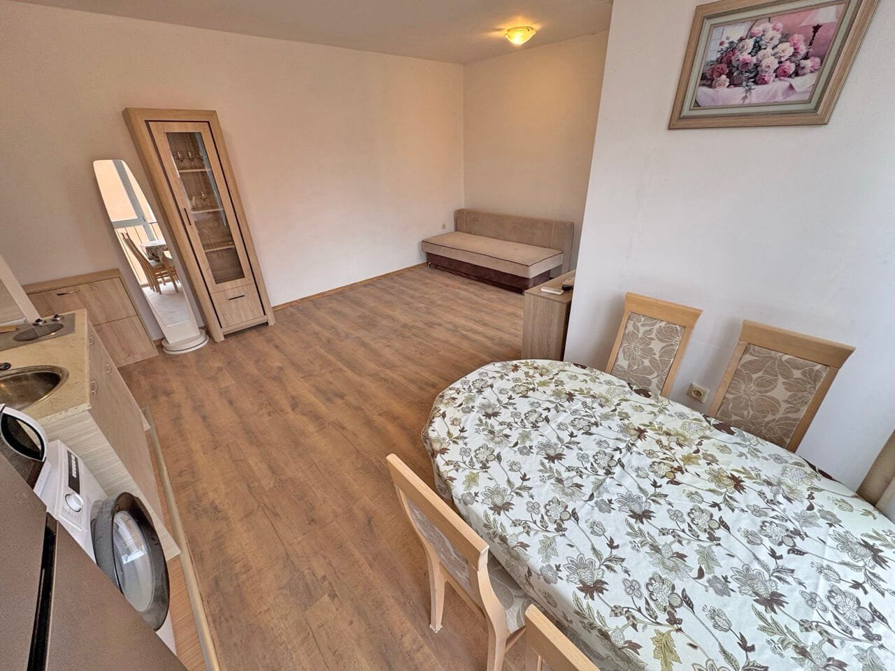 Гостиная с обеденным столом и стульями, светлые тона интерьера, диван, квартира в Болгарии, идеальна для отдыха у моря.