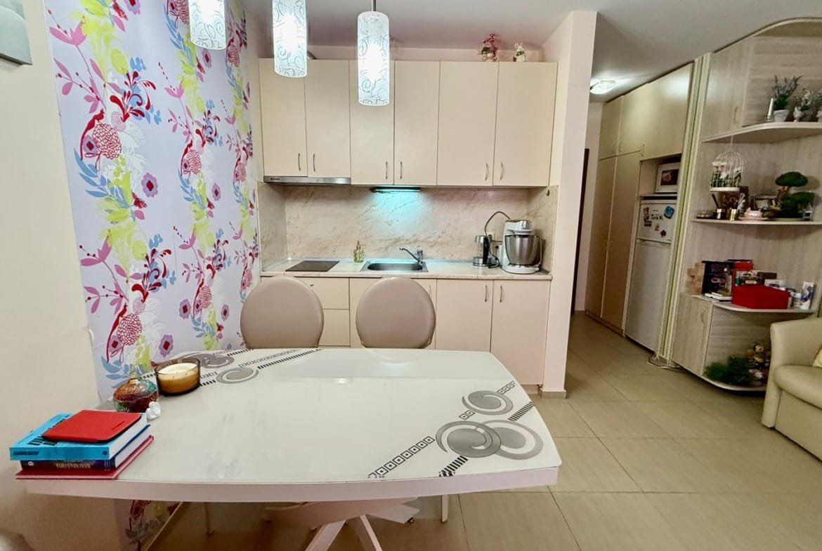 Современная кухня с обеденным столом, яркими обоями и бытовой техникой, идеальная для комфортного проживания в Болгарии.