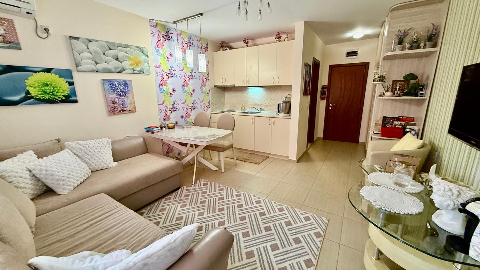 Современная уютная квартира в Болгарии с светлыми стенами, стильной мебелью и зоной для кухни и отдыха.