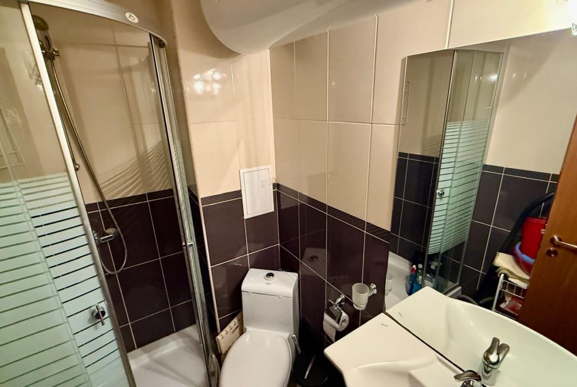 Современная ванная комната с душевой кабиной, унитазом и раковиной, оформленная в светлых и темных тонах для удобства.