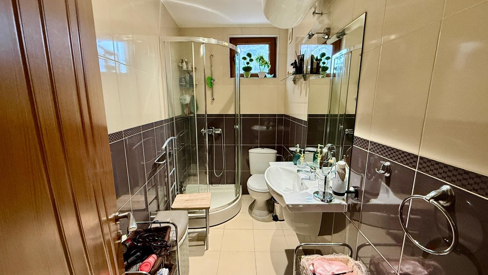 Светлая ванная комната с душевой кабиной, унитазом и раковиной, оформленная в современных тонах, подходит для жилья в Болгарии.