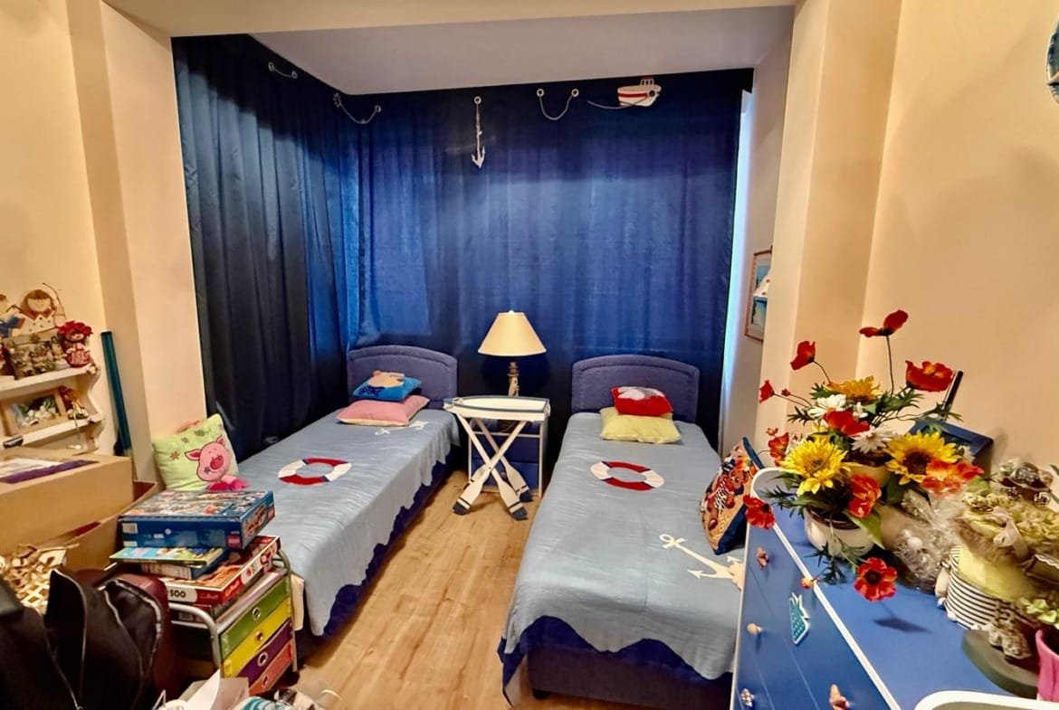 Комната с двумя одиночными кроватями, синими шторами и яркими декорациями, идеально подходит для аренды недвижимости в Болгарии.