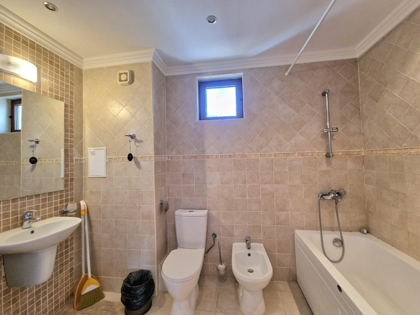 Современная ванная комната с плиткой, ванной, унитазом и раковиной, идеальна для продажи недвижимости в Болгарии.