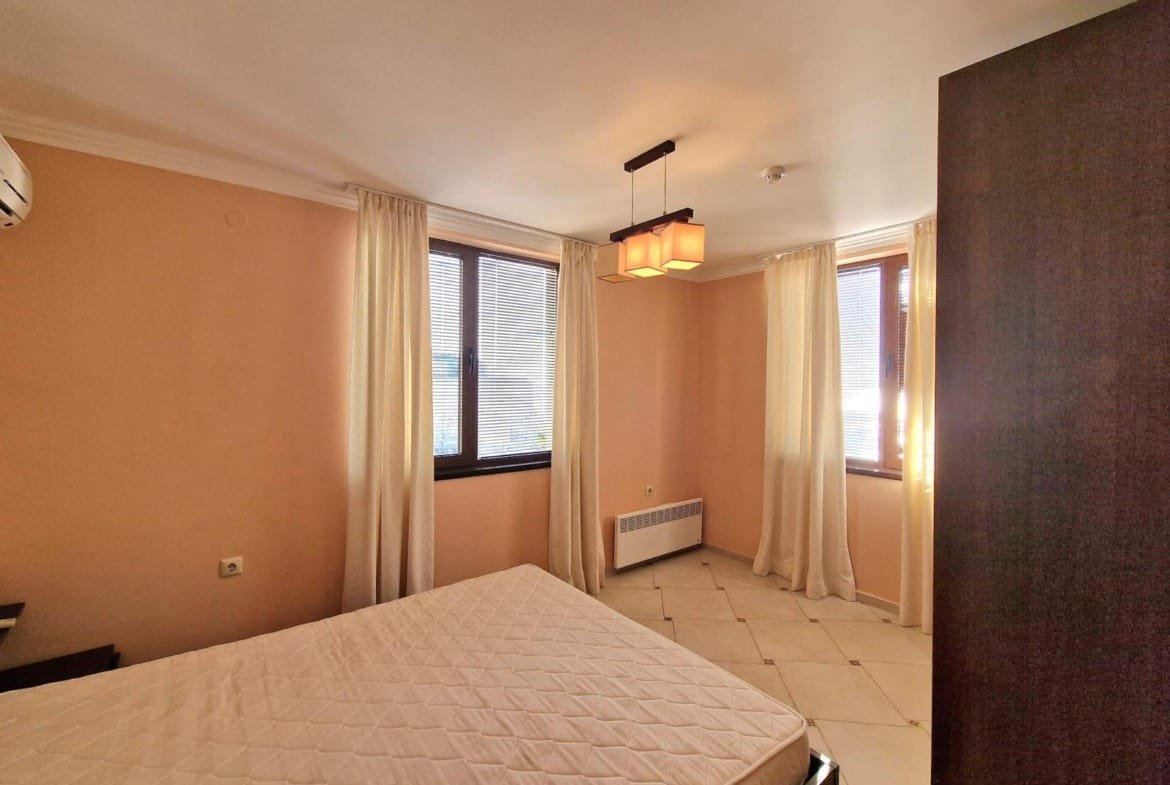 Светлая спальная комната с окнами, пастельные тона, пустая кровать и мягкие curtains, идеальна для покупки недвижимости в Болгарии.