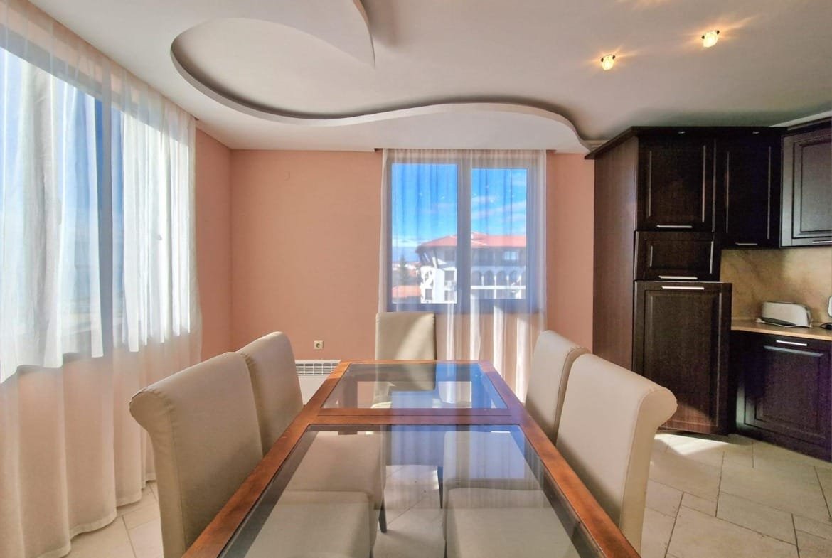 Современный интерьер квартиры в Болгарии, светлое помещение с окнами, стеклянным столом и уютной мебелью.