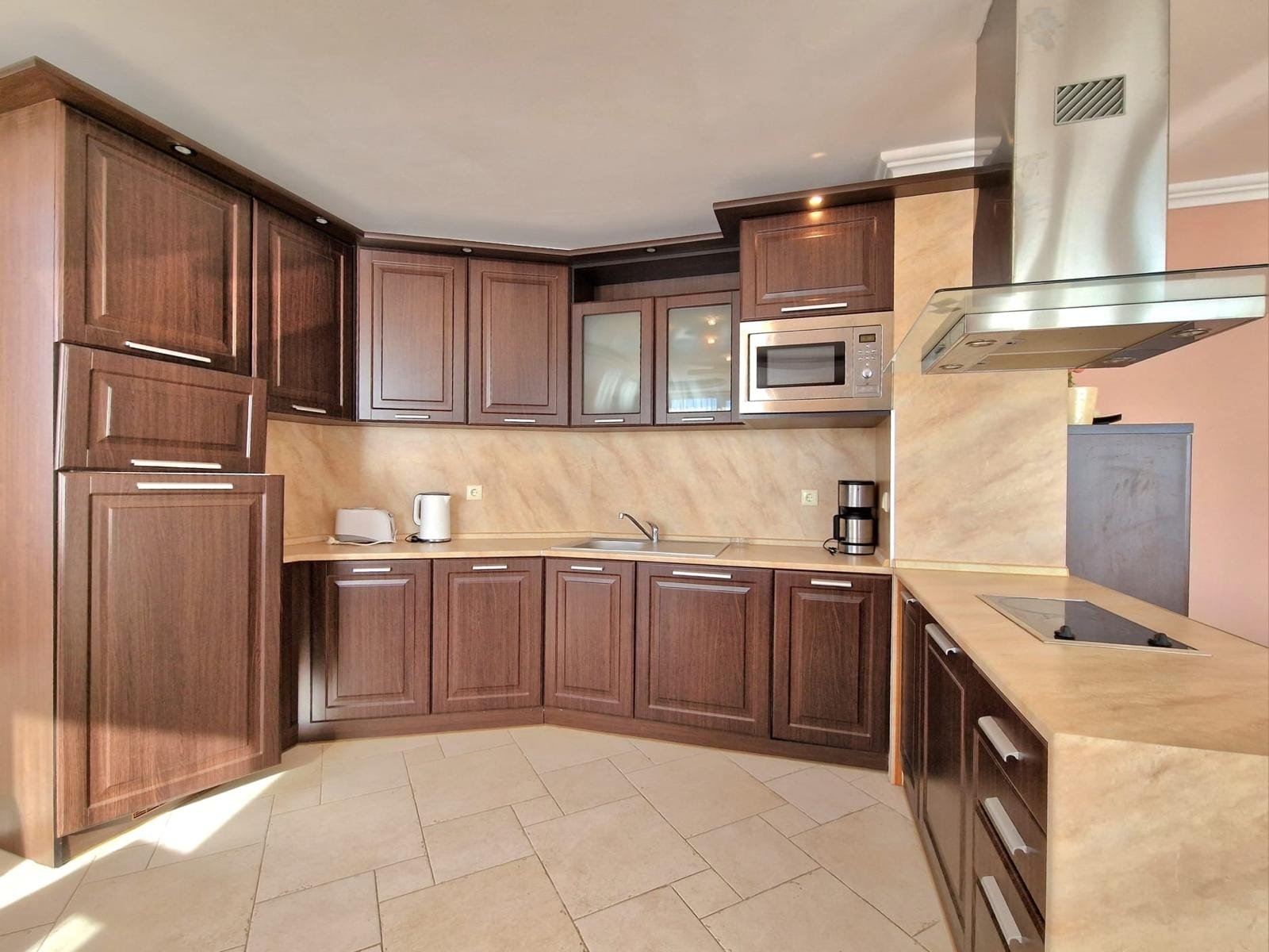 Современная кухня с деревянными шкафами и встроенной техникой, идеальна для продажи недвижимости в Болгарии.